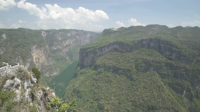 View of huge valley with high mountains and tropical jungle river at the bottom in sunny summer day