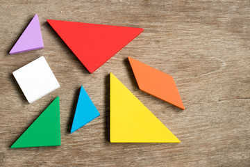 Straggled tangram puzzle  wait to complete the shape on wood background