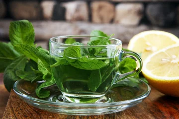 Photo sur Plexiglas Theé Cup of mint tea and leaves of mint on the table