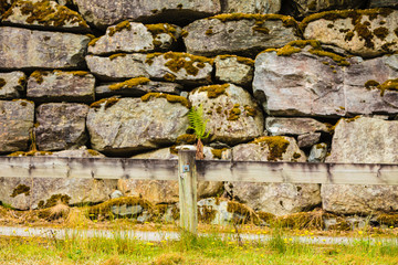 Fence and narrow path along wet stone wall