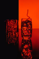 glass with water with ice cubes on a red round background