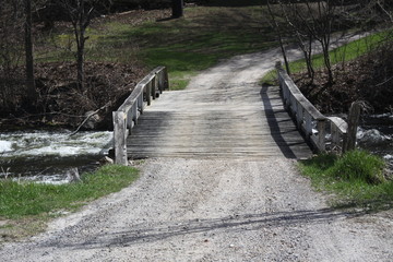 Wooden bridge spanning a fast moving creek full of water. 