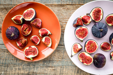 Plate of fresh blue figs on wooden background top view