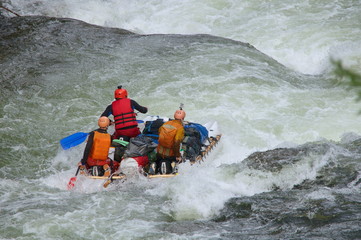 Team of people on an inflatable catamaran rafting on white water. Chaya river, North Baikal Highlands, Siberia, Russia.