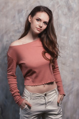 Young beautiful girl in fashionable clothes posing near the wall