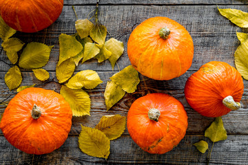 Pumpkin harvest. Pumpkins among autumn leaves on wooden background top view