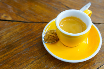 ristretto or espresso coffee shot in yellow cup with  spoon of brown sugar on old wooden table. copy space for text.