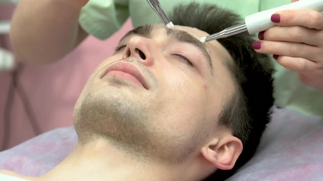 Microcurrent face therapy close up. Young man, cosmetology procedure.