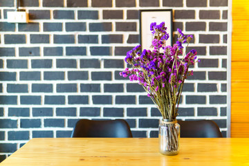 purple flower bouquet in on the wooden table with blurred brick wall background.