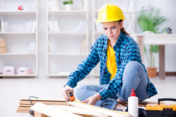 Female repairman carpenter cutting joining wooden planks doing r