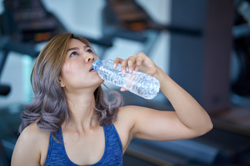 Asian women drink water in the gym after exercise.