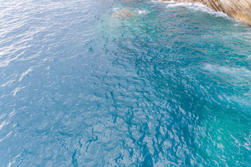 A bird's-eye view of how turquoise waves beat about sea cliffs in Montenegro