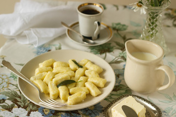 Homemade cottage cheese gnocchi or vareniki with sage oil. Useful breakfast. Gnocchi, coffee, milk. Rustic style, selective focus.