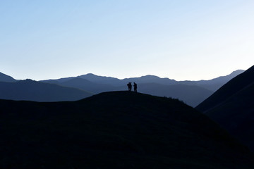 silhouette of people standing on the hillside