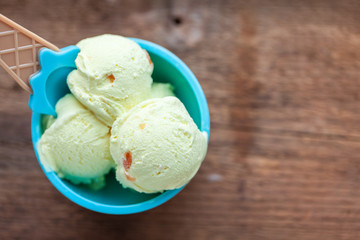 Vanilla ice cream with a taste of melon in a bowl on old wooden table.