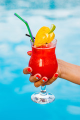 Glass with coctail with fruits near the pool