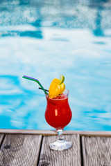 Glass with coctail with fruits near the pool