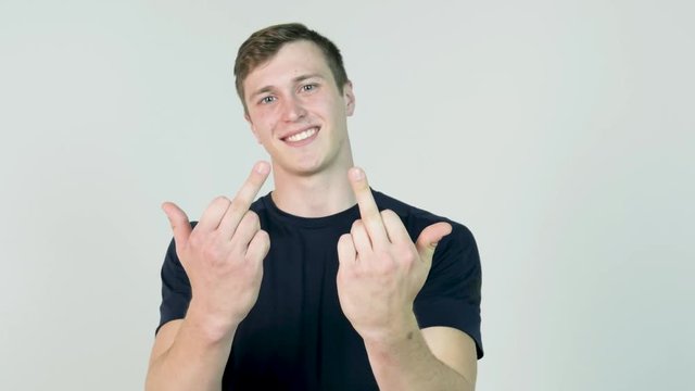 Young Man Showing Middle Finger Isolated on White. Young angry man with black t-shirt looking at camera and showing two middle finger