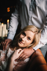 beautiful bride sitting on a chair in a beautifully decorated room with groom's hand on the shoulder