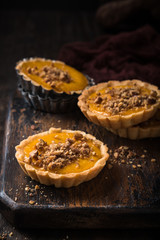 Pumpkin mini pie, tartlet made for Thanksgiving day on old wooden background. Healthy autumn food concept with copy space. Dark photo.