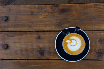 close up ,top view of hot latte in dark blue cup with spoon on the wooden table. copy space for your text.