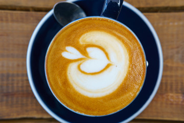 close up ,top view of hot latte in dark blue cup with spoon on the wooden table. copy space for your text.