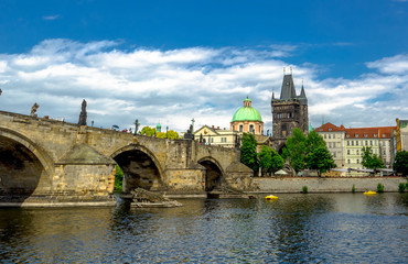 Fototapeta na wymiar Landscape of the romantic city of Prague under a blue sky. Panoramic view of Charles bridge and old town on a summer day in the capital Czech Republic. Cruise on the Moldovan river.