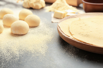 Wooden plate with rolled dough and balls for tortillas on kitchen table