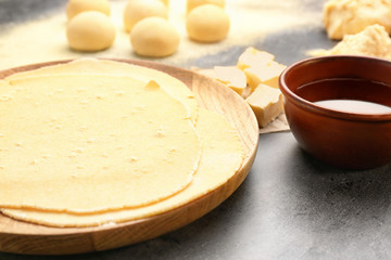 Wooden plate with rolled dough for tortillas on kitchen table