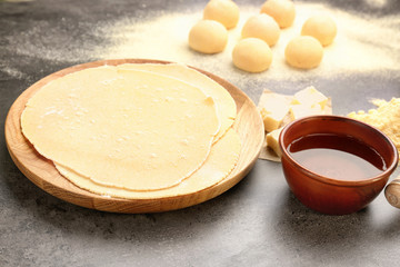Wooden plate with rolled dough for tortillas on kitchen table