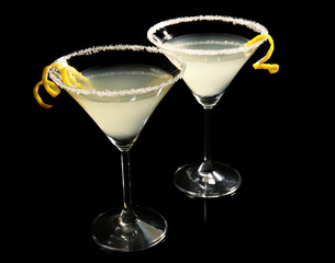 Glasses of lemon drop martini with zest on black background