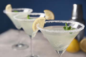 Glass with tasty lemon drop martini cocktail on blurred background, closeup