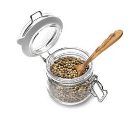 Jar with hemp seeds and spoon on white background