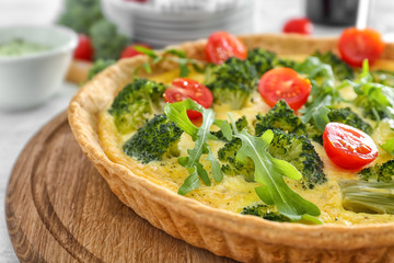 Tasty broccoli quiche on wooden board