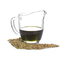 Jug with hemp oil and seeds on white background