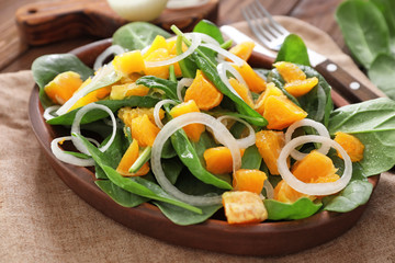 Plate with salad with spinach and orange on table