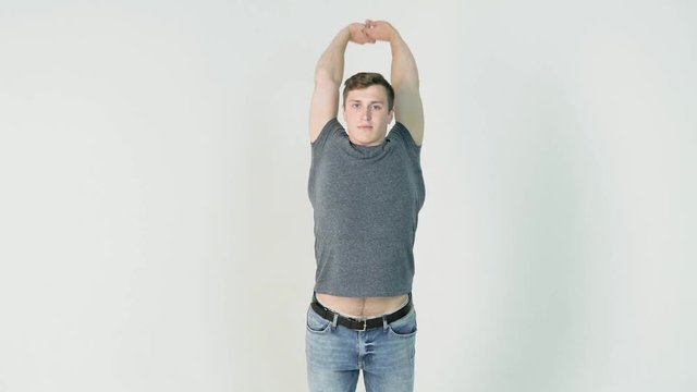 Young smiling man athlete doing warming exercises on white background. Concept of sport, health, keeping fit
