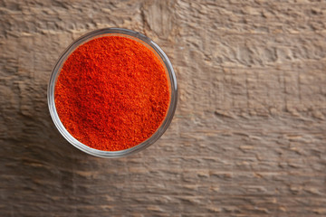 Chili powder in bowl on wooden background