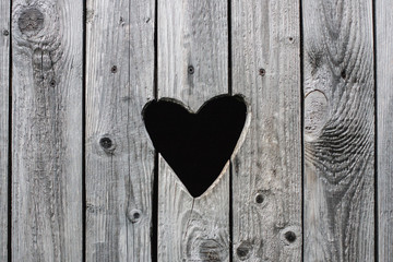 Old vintage rural toilet door with a heart shaped hole in the wooden shutters background