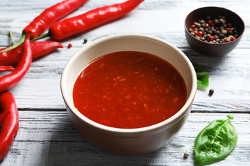 Ceramic bowl with chili sauce on wooden background