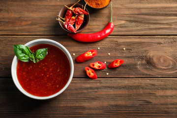 Composition with chili sauce on wooden background
