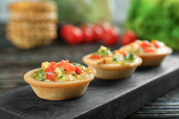 Board with broccoli quiche tartlets on table