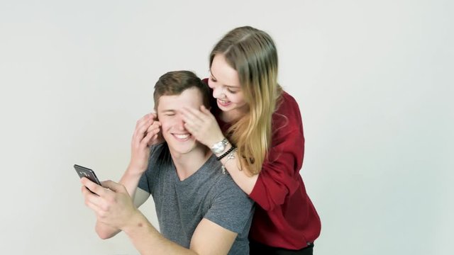 beautiful happy smiling woman covering eyes with her hands of handsome young man in fun mood