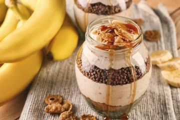Glass jar with yummy banana pudding on kitchen table, closeup