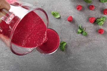 Pouring tasty smoothie into glass on table