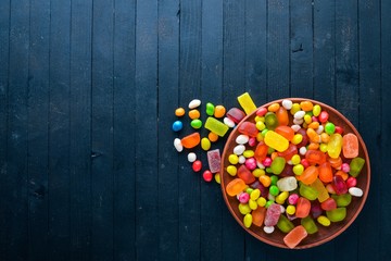 Colored candies, sweets and lollipops. On a black wooden background. Top view. Free space.