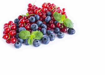 Ripe blueberries and red currants with mint. Berries at border of image with copy space for text. Red and blue berries. Various fresh summer berries on white background.