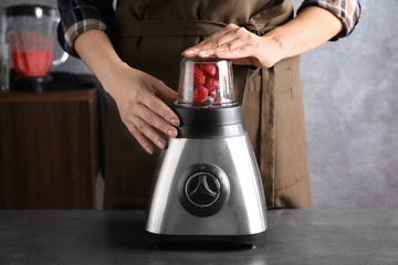 Young woman preparing smoothie in kitchen