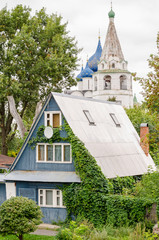 Fototapeta na wymiar View of a traditional wooden house and the Suzdal Kremlin in the background