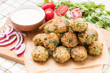 falafel balls on paper and wooden board with vegetables